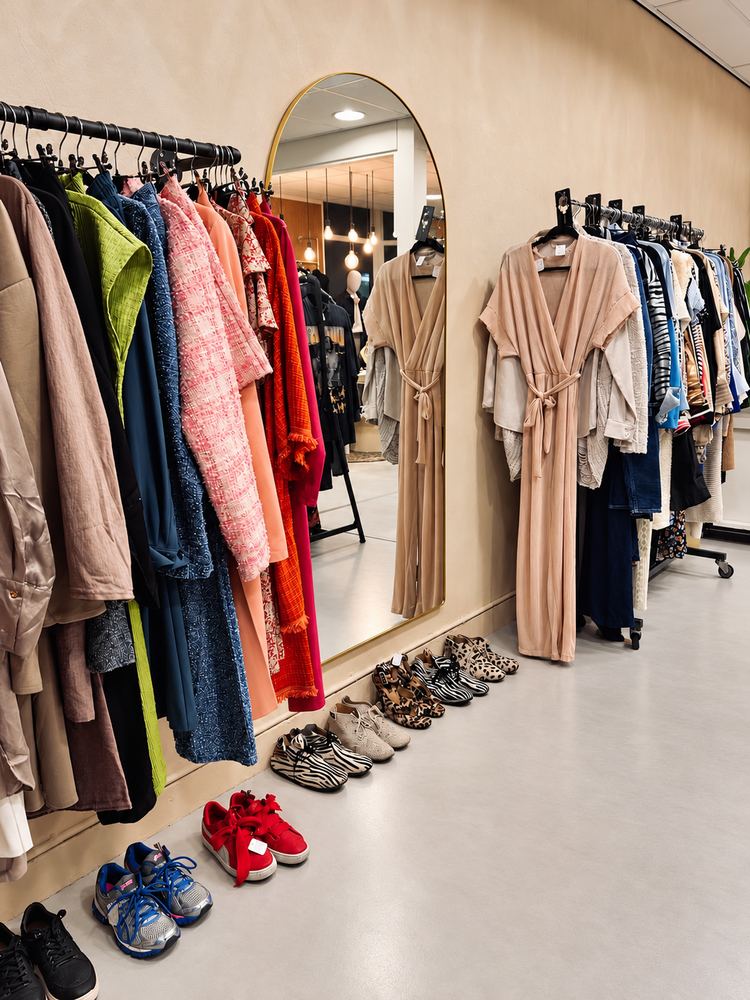 Lange wand met kleding, schoenen en een staande spiegel